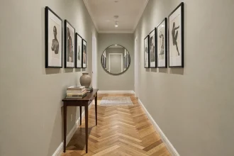 Couloir étroit décoré en galerie d'art avec cadres noirs, console en noyer et miroir rond au fond