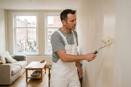 Peintre professionnel appliquant de la peinture crème sur un mur intérieur dans un salon moderne